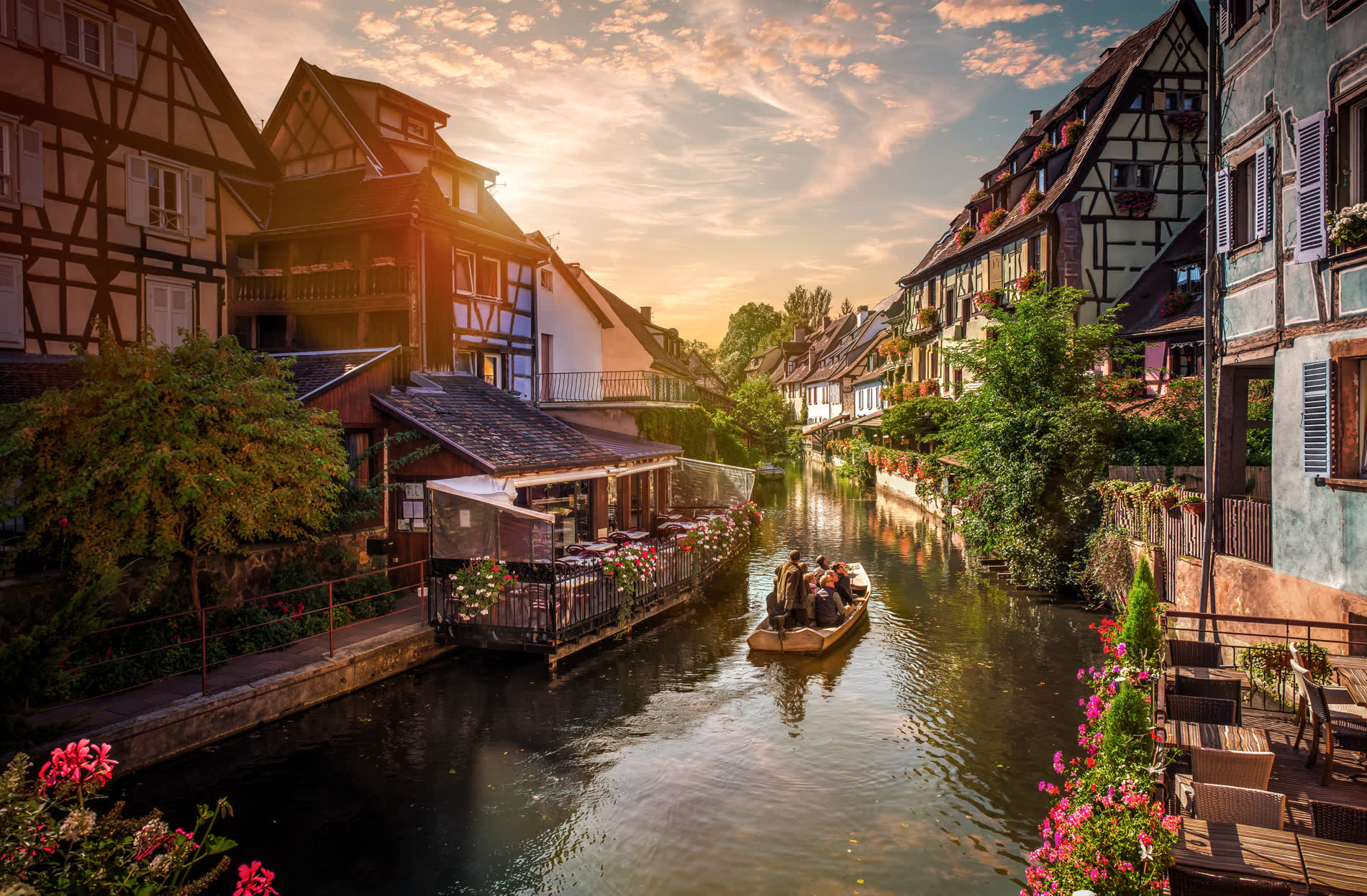 Kanal zwischen bunten Fachwerkhäusern mit Blumenkästen, ein Boot auf dem Wasser